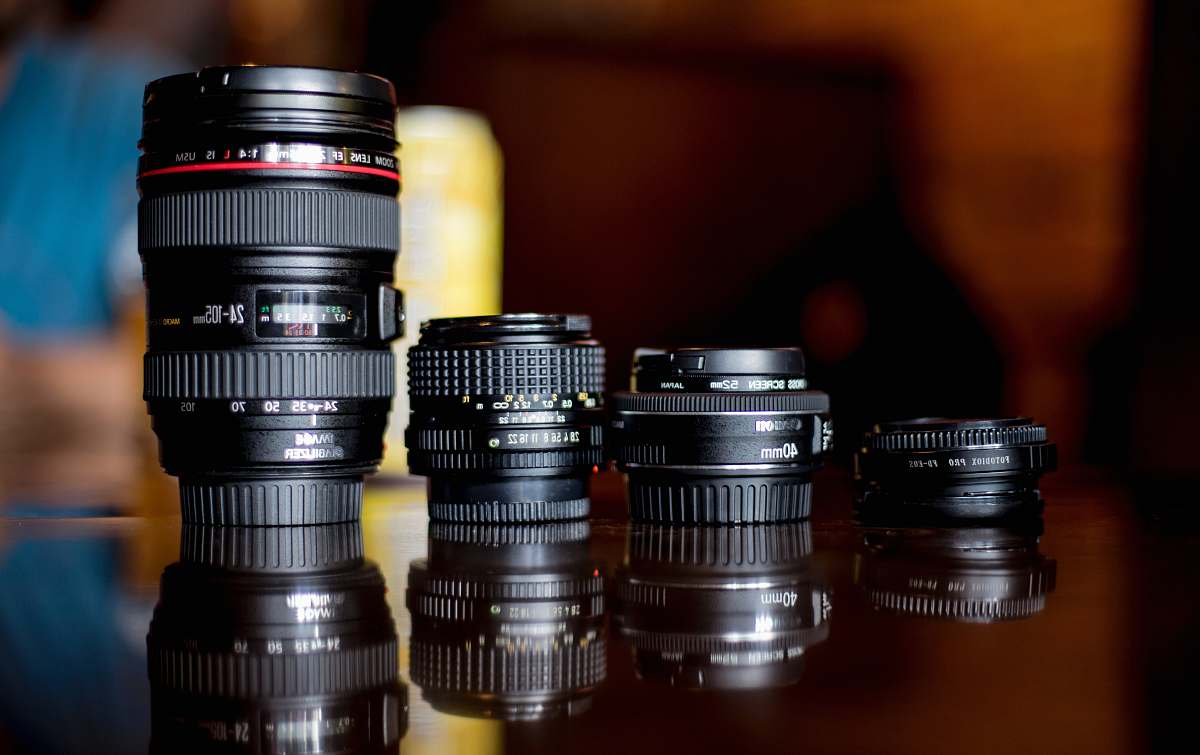 electronics selective focus photography of four black DSLR camera lens on brown wooden surface len